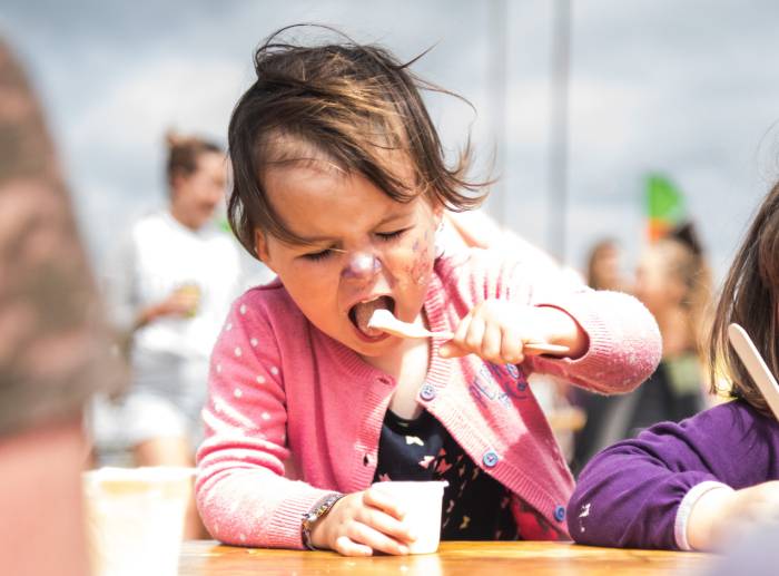 small child eating organic yogurt at festival
